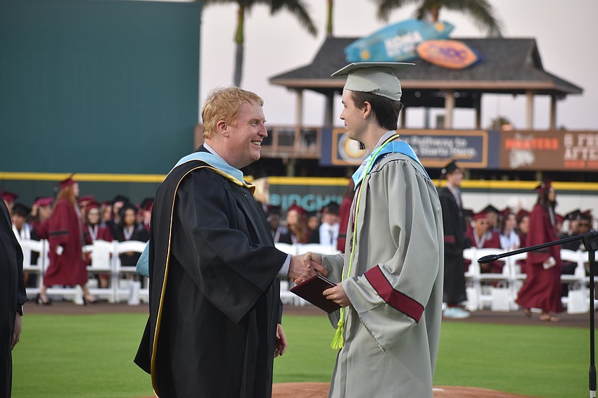 Superintendent Jason Wysong gives a handshake to valedictorian James Daley.