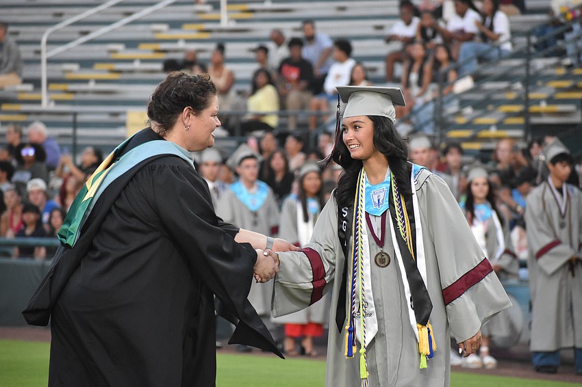 Assistant principal Rebecca Austerman shakes hands with commencement speaker Louann McCord.