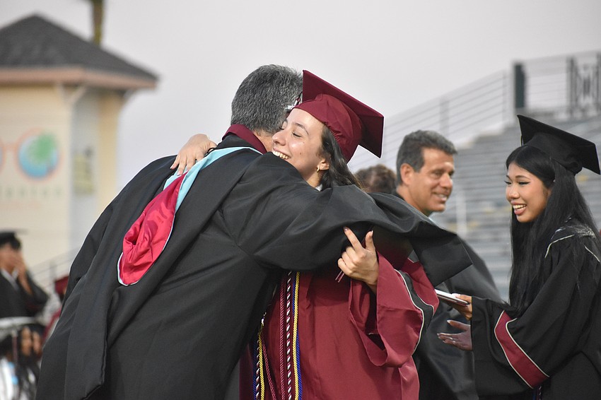 Gloria Candela  receives a hug from assistant principal Matthew Whelden as she receives her diploma.