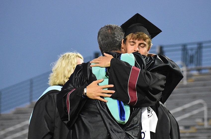 Graduate Nicholas Nesser and athletic director Matthew Nesser share a hug as Nicholas receives his diploma.