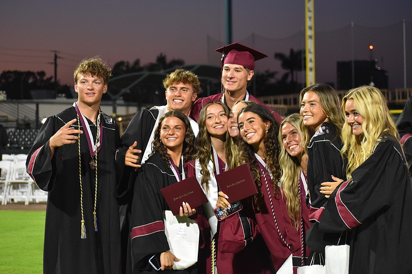 A large group of graduates pose for a photo after the commencement ceremony at LECOM Park.