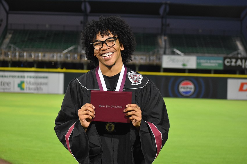 Micaiah DeSue beams with pride as he shows off his diploma.
