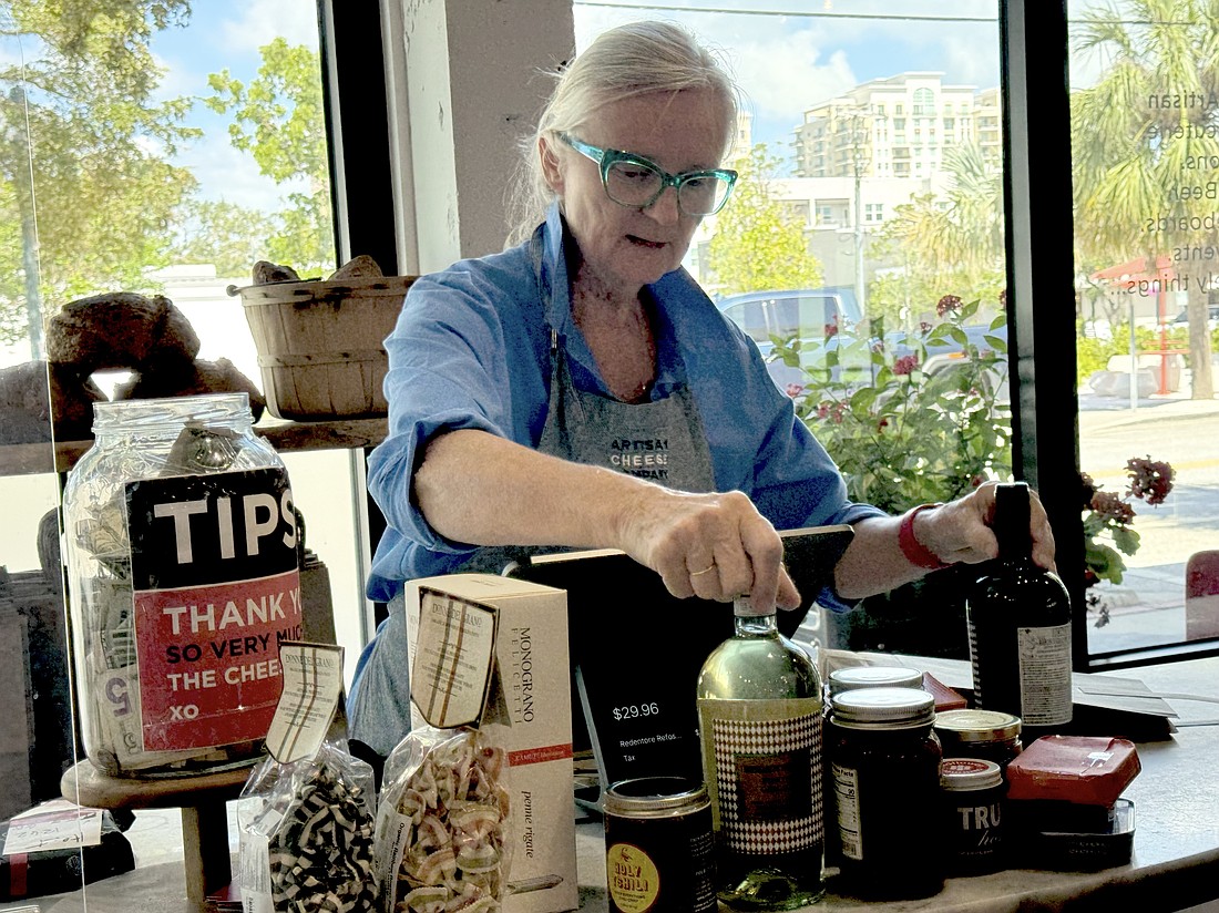 Artisan Cheese Company owner Louise Converse rings up a customer buying wine, cheese, pasta and accoutrements.