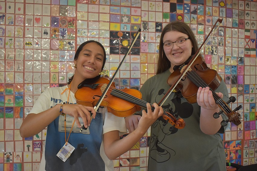 Mariella Martinez Reyes, a seventh grade student who plays violin, and Elizabeth Argo, an eighth grader who plays viola, provide musical entertainment while visitors look at the art.