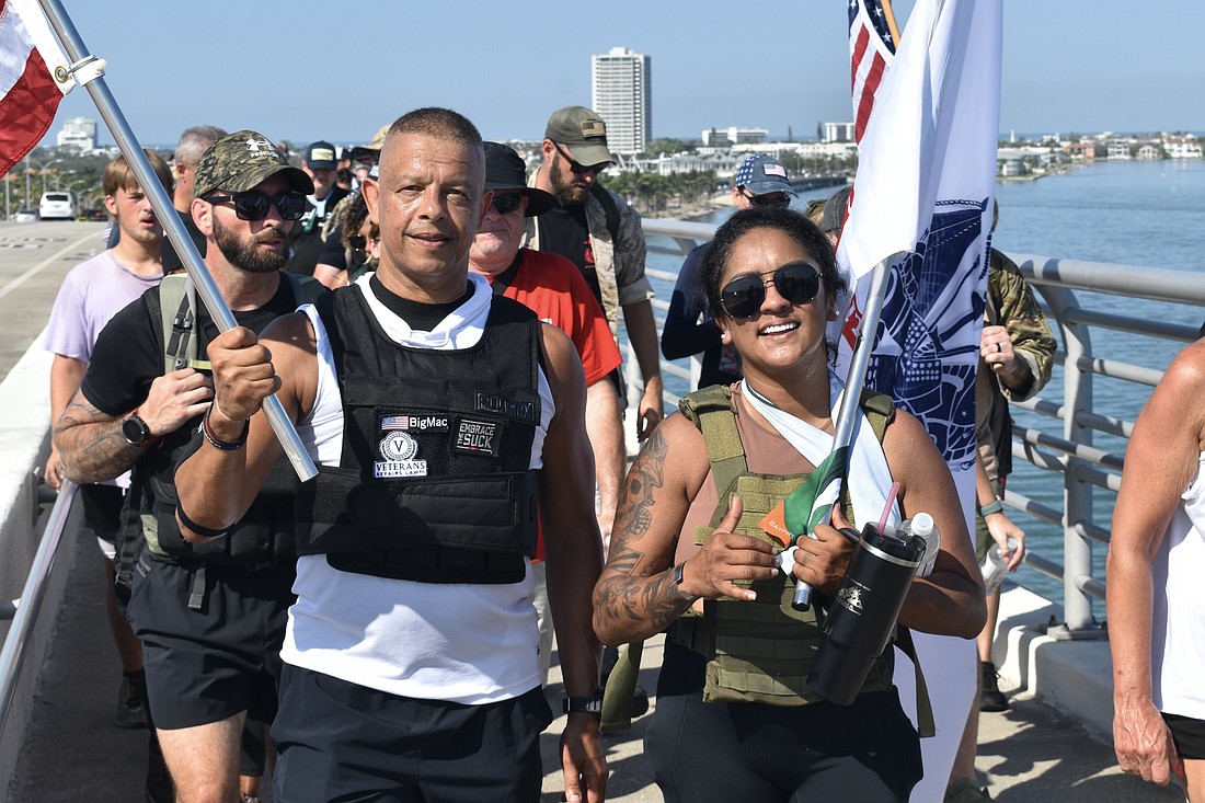 Tommy Madi of Slim Chickens, which provided food at the event, and his friend Maria Guardado, walk over the Ringling Bridge.