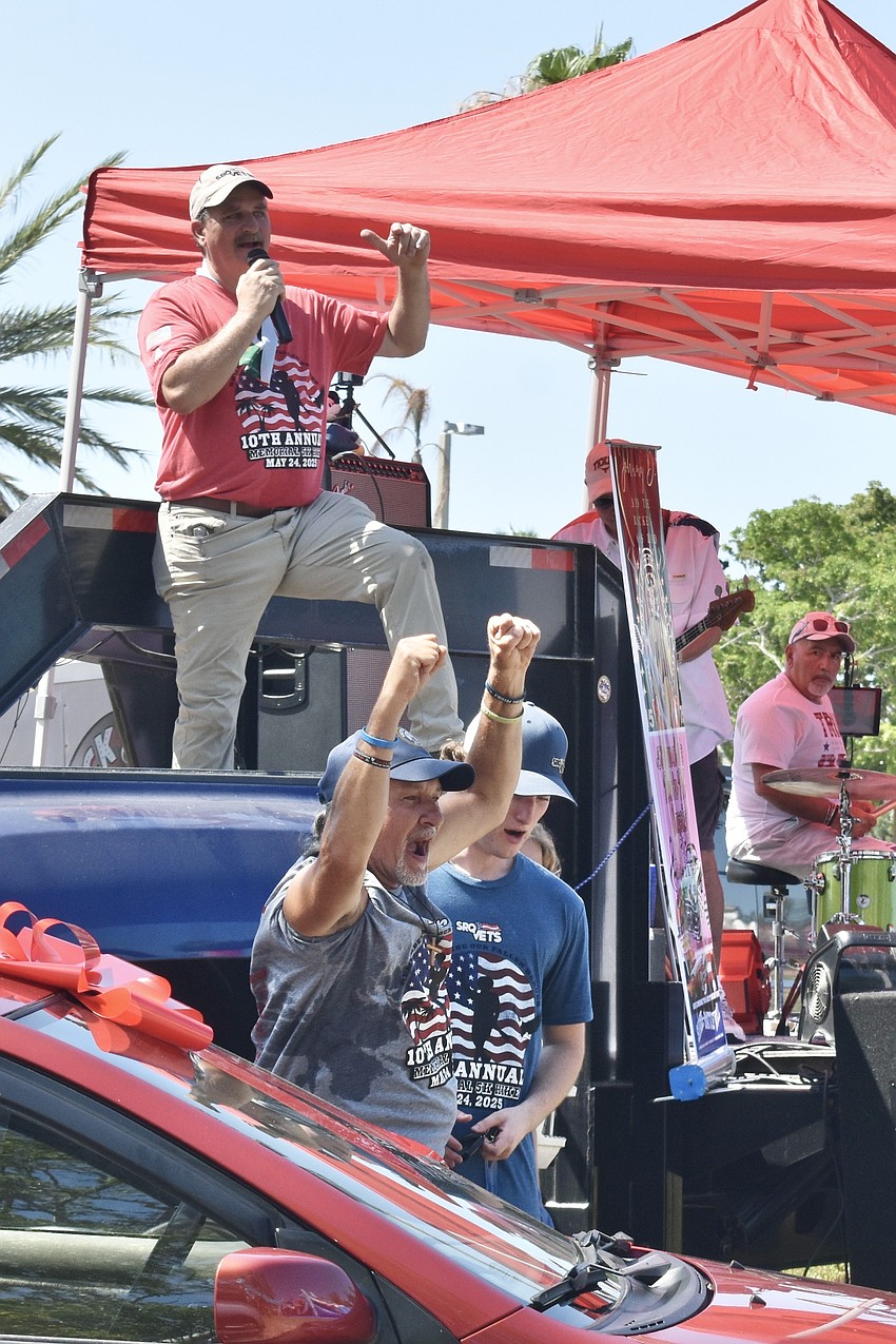 Rob Kehs announces the donation of the vehicles, as veteran David Mattis cheers for his new car, standing next to Preston Kehs.