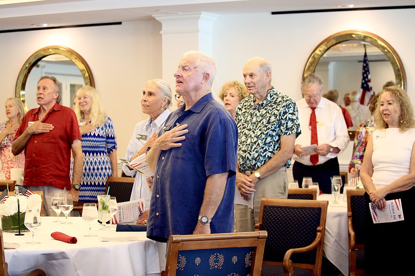 Attendees join in singing the National Anthem, led by soloist Loraine Murphy.