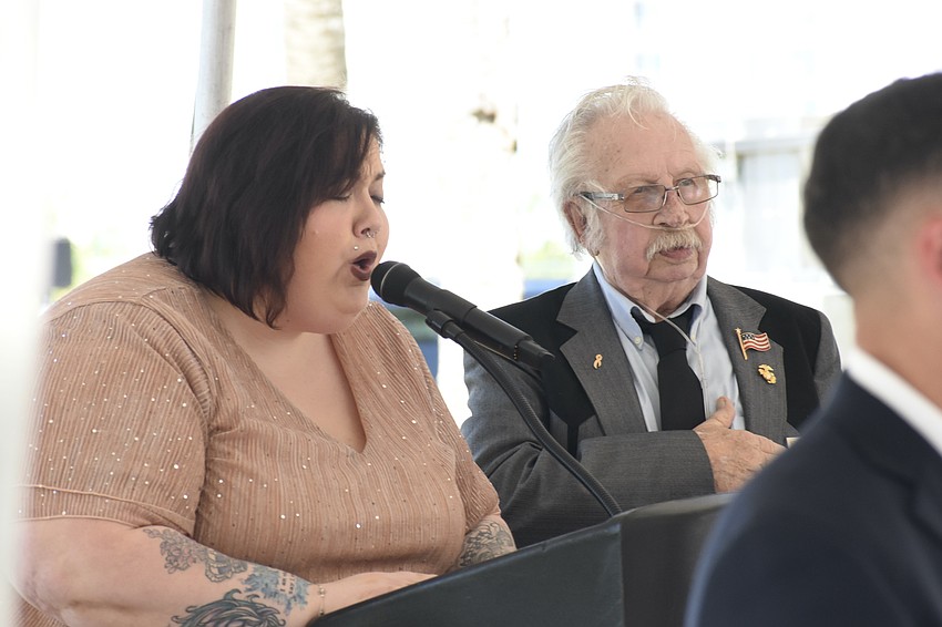 Megan Ronan sings the National Anthem as she stands beside Sonny Bywaters.