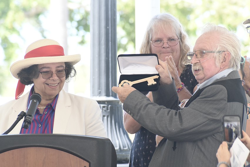 City Commissioner Debbie Trice (left) presents the key to the city to Sonny Bywaters (right), as Bywaters' daughter Cheryl Hugh applauds.
