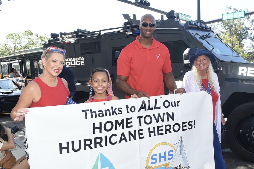 Tricia Ward, her daughter Violet Ward, 8, and her husband Jerrod Ward hold a banner promoting hurricane relief, with Jan Solomon.