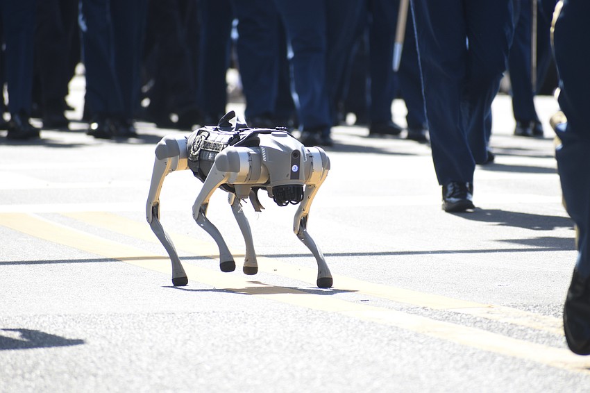 A robot dog walks beside Sarasota Military Academy students.