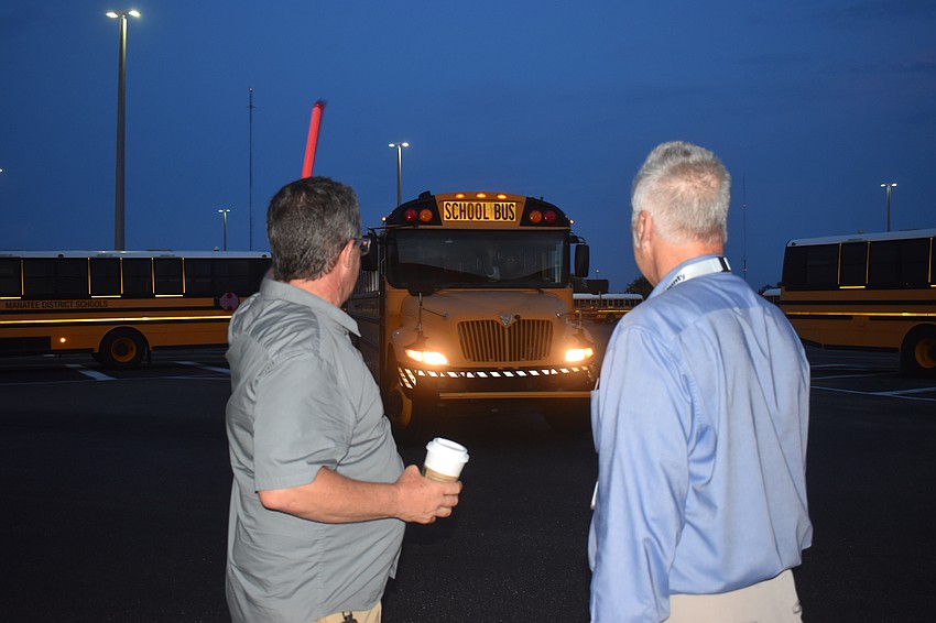 School Board Member Charlie Kennedy and Communications Director Mike Barber give a wave as the bus drivers leave on the final day of school Thursday.