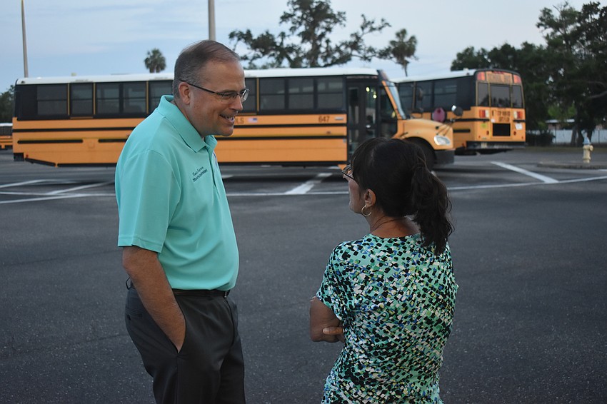 Interim superintendent Kevin Chapman and school board member Cindy Spray are among the early risers to wave off the bus drivers.