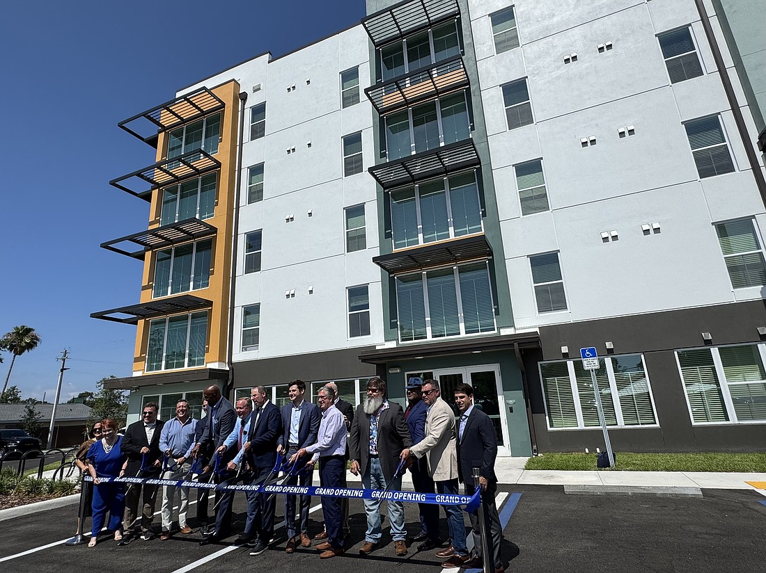 Elected officials, NBA legend Alonzo Mourning and others who helped develop Astoria on 9th with Housing Trust Group cut the ribbon outside the apartment complex.