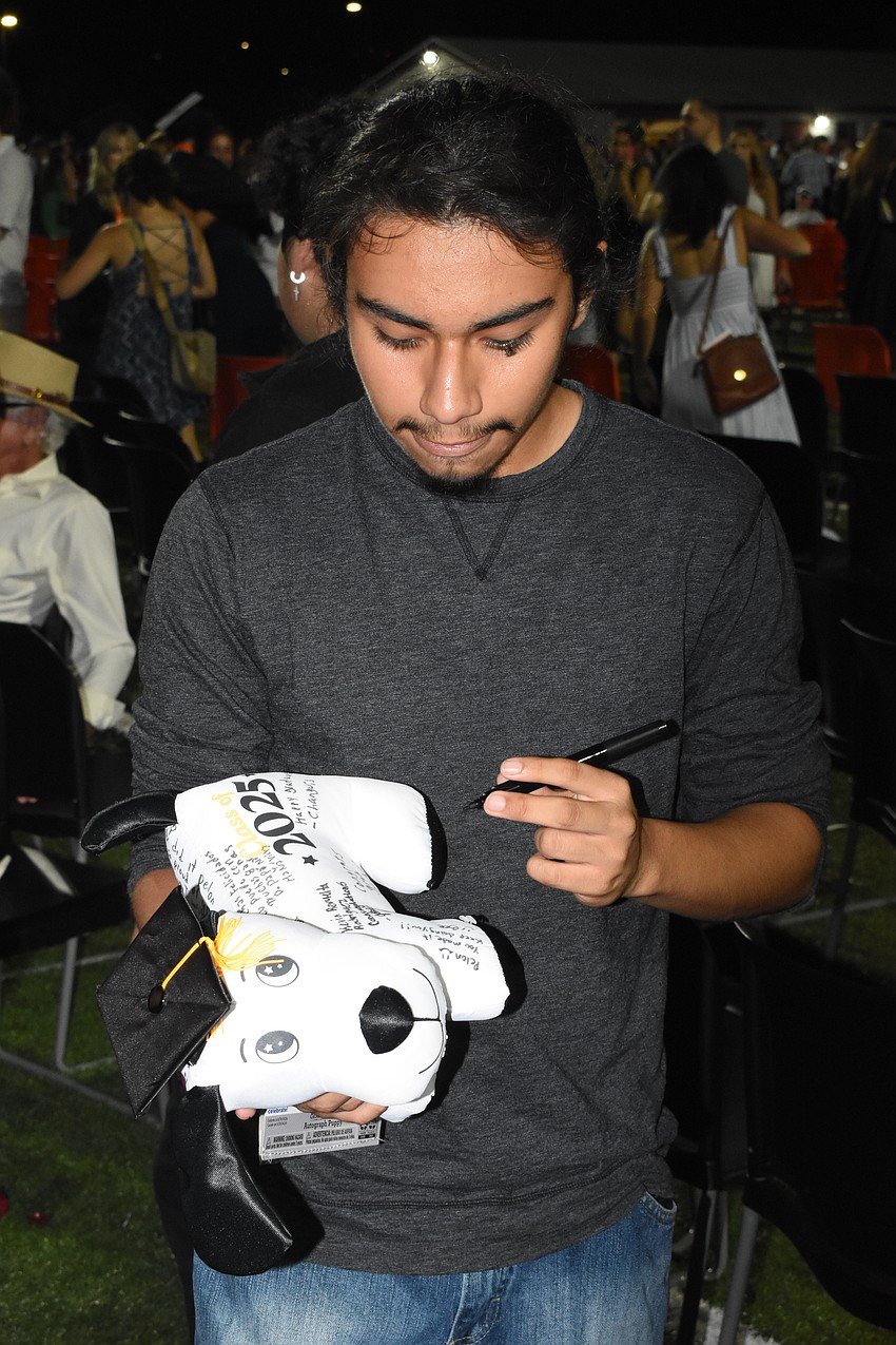 Jose Aguilar signs a stuffed animal for graduate Jorge Ricardo.