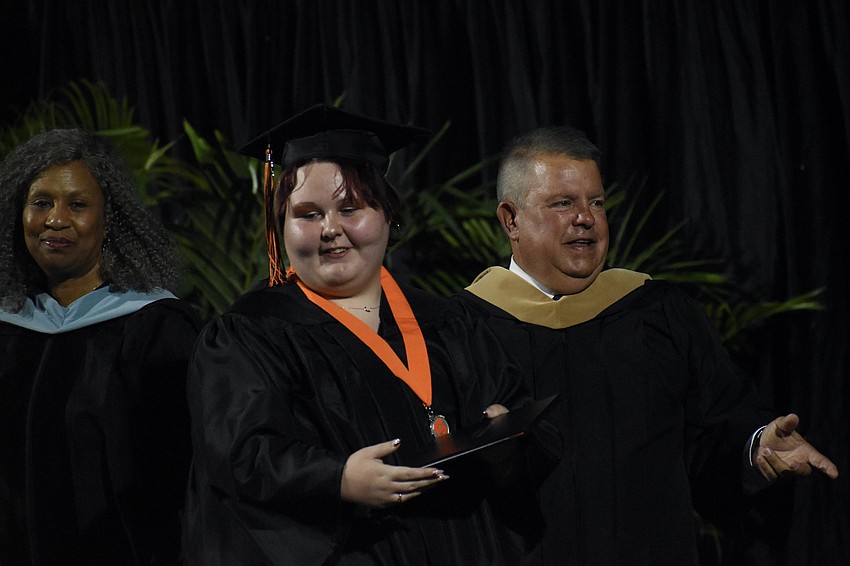Cierra Driggers (center) leaves the stage after greeting Director of Strategic Engagement Harriet Moore and School Board Chair Tim Enos.
