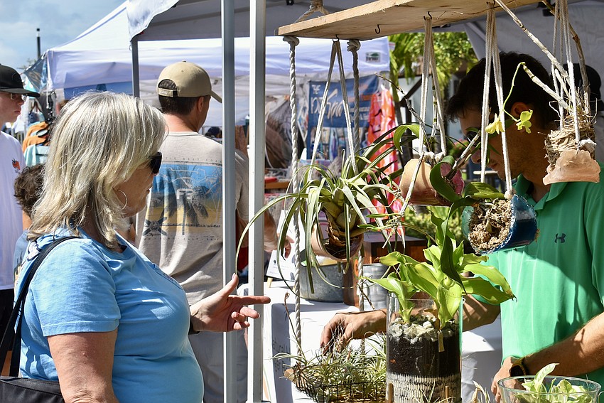 Parrish's Debbie Kay stops to ask a couple questions at Aqutra Products, which sells succulents and air plants in handmade epoxy resin plant hangers.