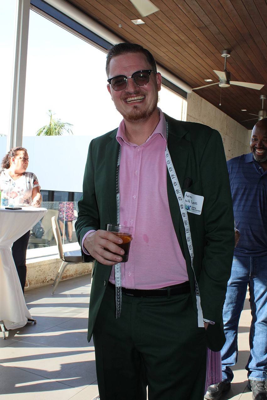 Andrew Sweetnich of Tweeds custom suits dons a measuring tape while meeting with fellow businesspeople.