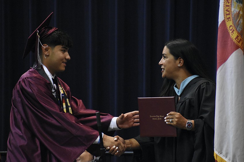 Raul Batista receives a diploma from Deputy Superintendent and Chief Academic Officer Rachael O'Dea.