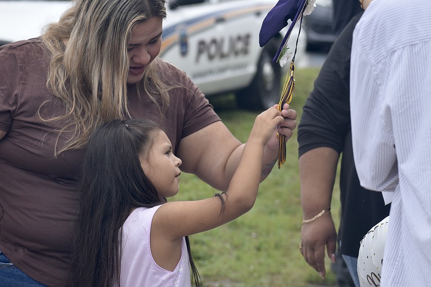Elizabeth Galvan and her daughter Amaya Galvan-Cornier, 6, touch a tassel on the cap of Galvan's cousin Mia Carrillo, who graduated along with Elizabeth Galvan's sister Jayla Galvan.