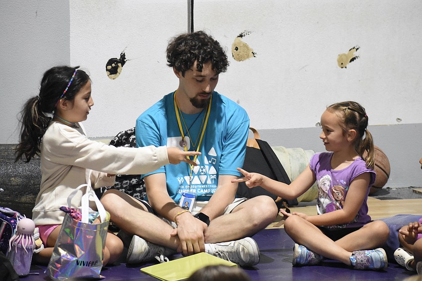 Viviana Quiles 7, counselor Aydin Frazier and Nila Molineaux, 6 play rock, paper scissors.