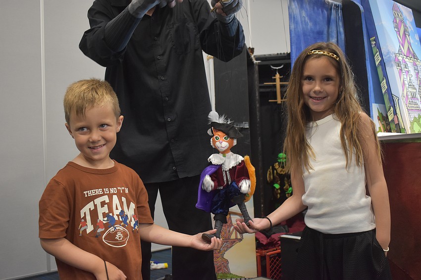 Juliana Born, 6, and Troy Born, 4, explore the puppets of Puss in Boots after seeing the live puppet show.