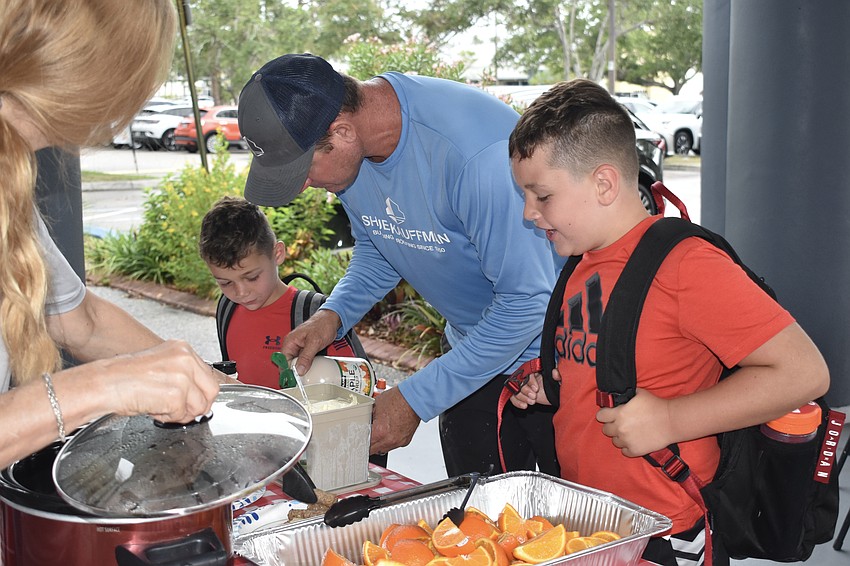 Clark Mast, 5, his father Nelson Mast, and brother Parker Mast, 8, gather breakfast.