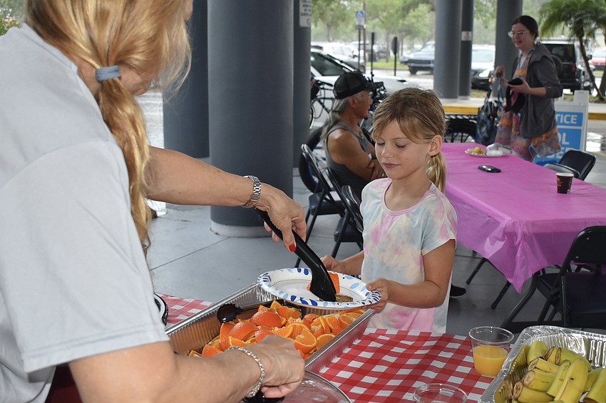 Laura Walters offers food to Leila Stevenson, 7.