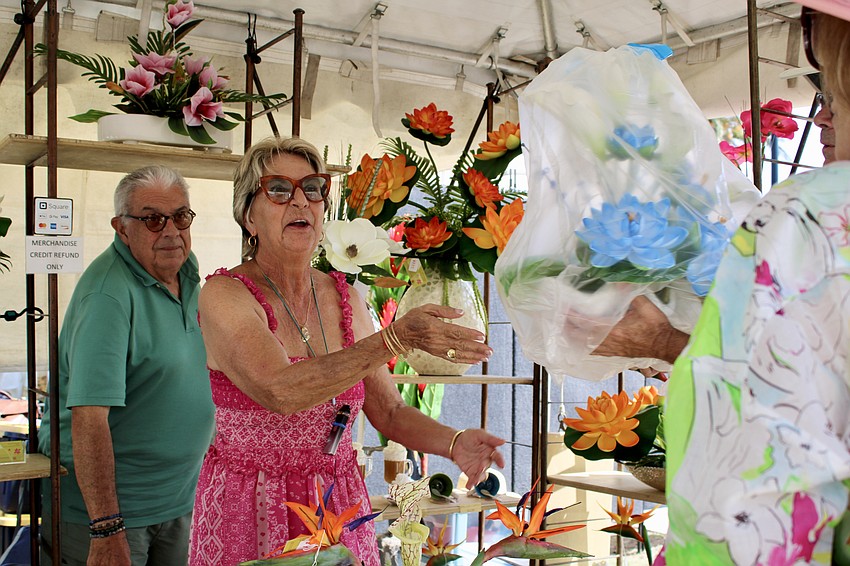 Designer Patricia Campuzano hands over an order to a customer while her husband, Carlos, explains the care instructions for their floral latex art sculptures.