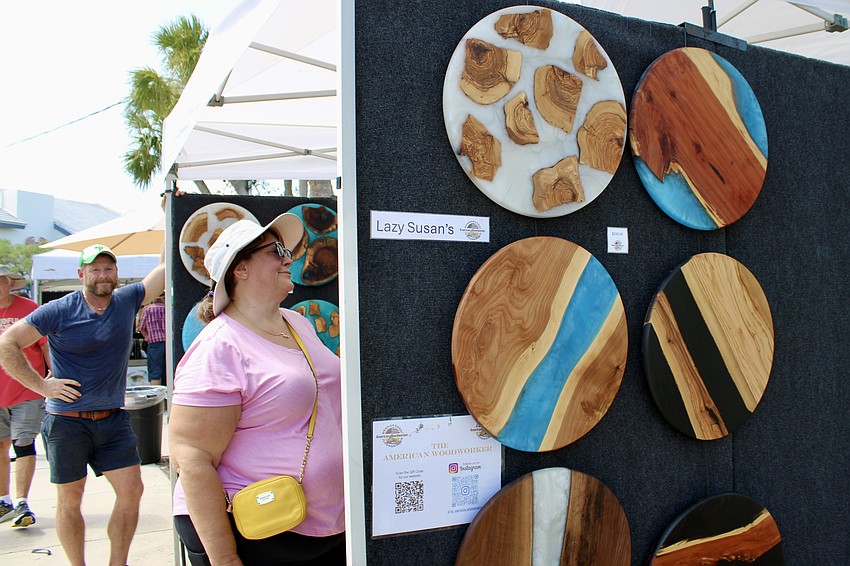 An attendee at the St. Armands Circle Craft Festival carefully examines one of Robin Roberts' handcrafted pieces while he looks on.