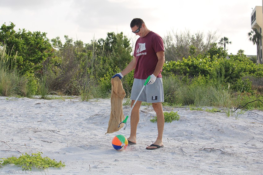Volunteer Robert Szucs uncovers an abandoned beach ball during a World Ocean Day cleanup at Siesta Beach.