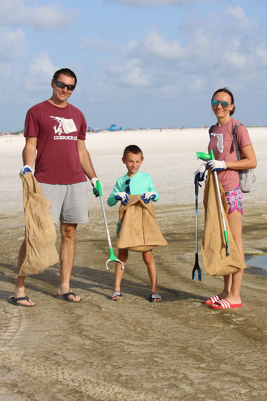 Robert Szucs, Bence Scucs and Timea Hullar help out with the Siesta Beach cleanup.
