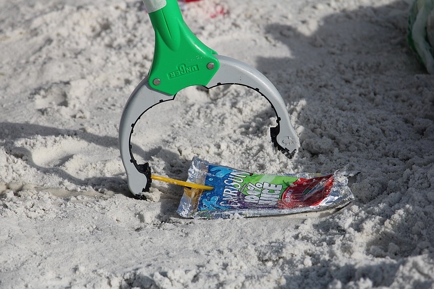 Volunteer Jerry Uhl snaps up a juice pouch while clearing litter from Siesta Beach.