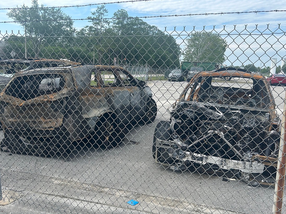 Cars damaged in the Jacksonville International Airport parking garage fire sit in a parking lot off Pecan Park Road.