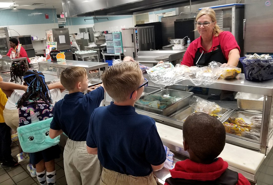 Students receive a meal in a school dining area.