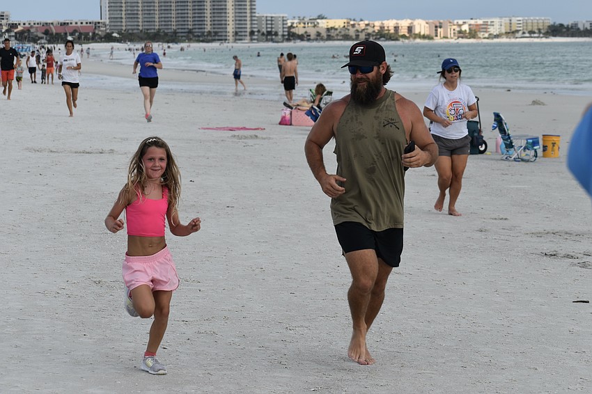 Camdynn Hogan, 6, and her father Cory Hogan make their way towards the finish line.