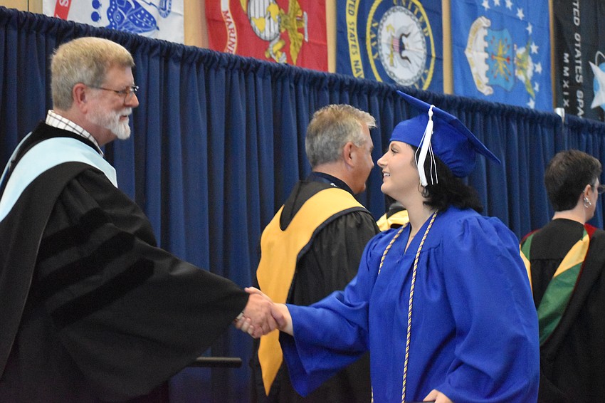Paul Gansemer, the executive director of adult, career and technical education for the School District of Manatee County, congratulates Sophia Swim, an MTC graduate in digital videography technology.