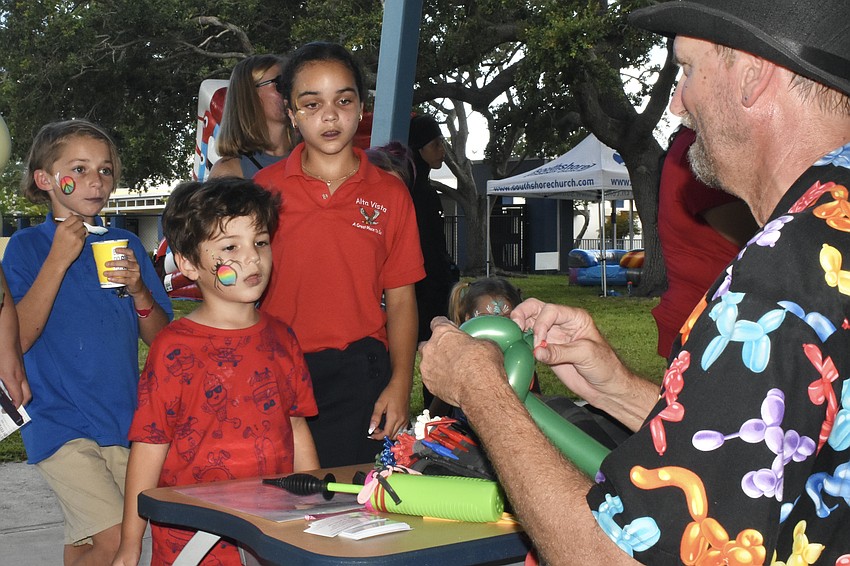 Hannah Harden, 10, Tristan Artah, 4 and Leah Nune, 9, watch as MisterRon twists a balloon.