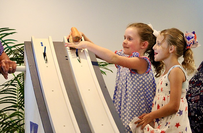 Emma Bailey Gaddy and Vivienne Hansen carefully line up their potato race car at Bird Key Yacht Club's Fourth of July festivities.