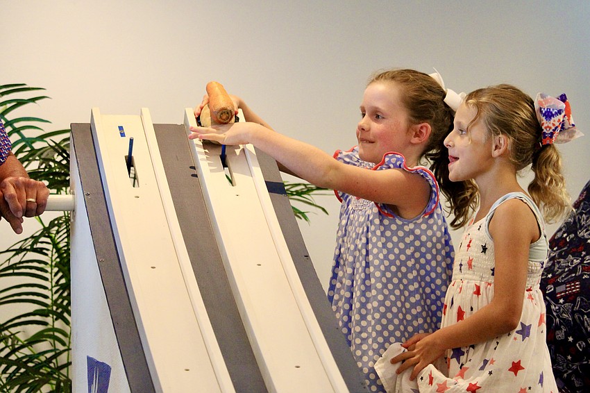 Emma Bailey Gaddy and Vivienne Hansen carefully line up their potato race car at Bird Key Yacht Club's Fourth of July festivities.
