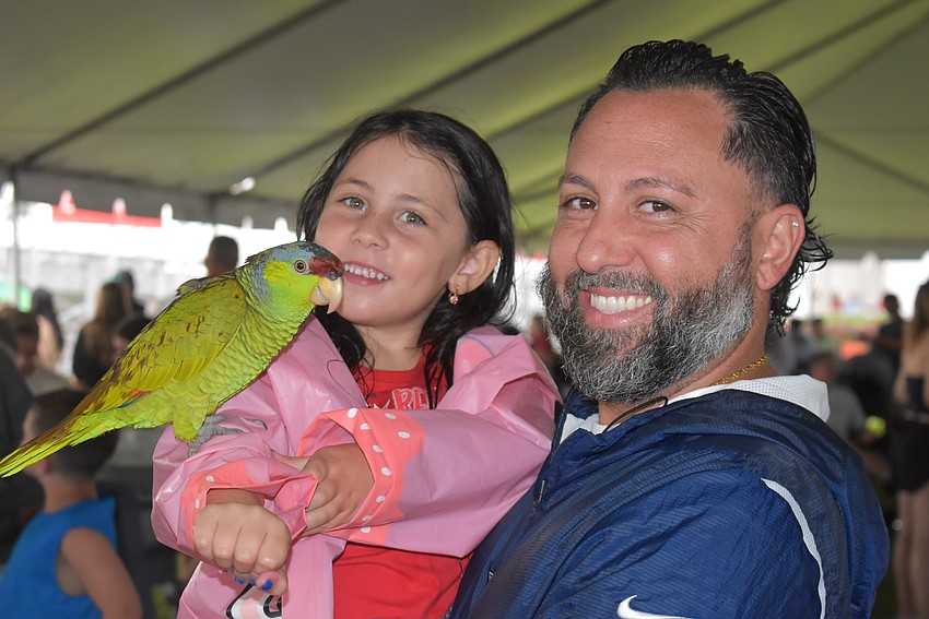 John Geraci holds his 4-year-old daughter Luna, and Luna holds Taco the parrot during Fireworks on the Lake. Luna said she fed a bird once, but this is her first time holding one.