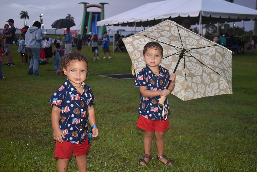 Sarasota's Matthew Perivolaris, 1, and Michael Perivolaris, 3, head out of the soggy Kids Zone after playing on the inflatables during Fireworks on the Lake at Nathan Benderson Park.