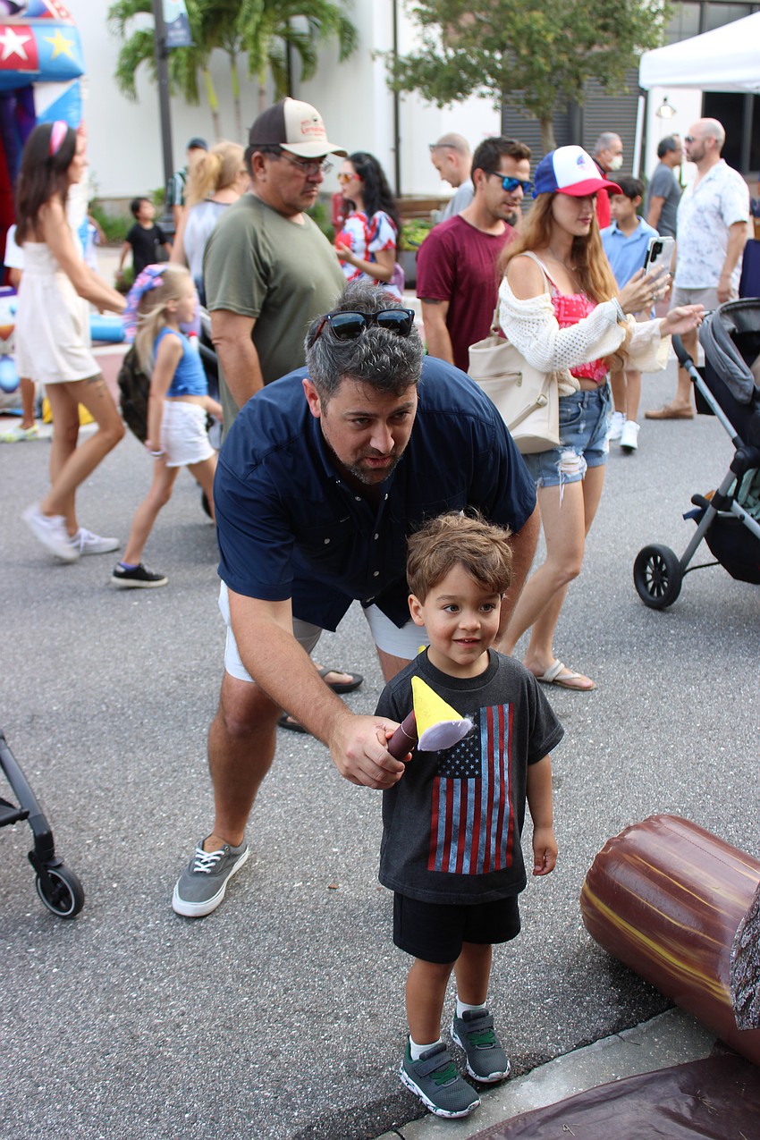 University Park's John Blackwell gives his 3-year-old son Jack a little help throwing the ax in a carnival game at Star-Spangled Spectacular.