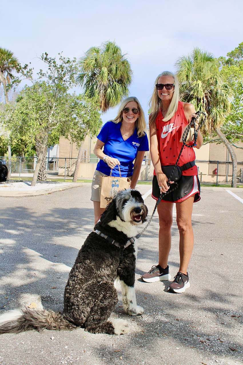 Diane Baade, right, and her 4-year-old shepherd-doodle mix, Sugar, collect a goodie bag from Linda Emery with Dog Perfect.