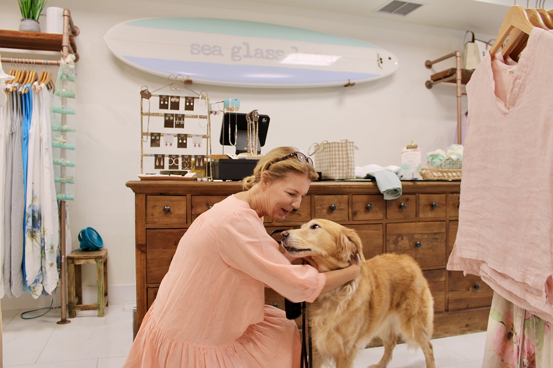 Finley enjoys some extra attention from Sea Glass Lane owner Manon Giguere as they oversee the boutique's moving sale.