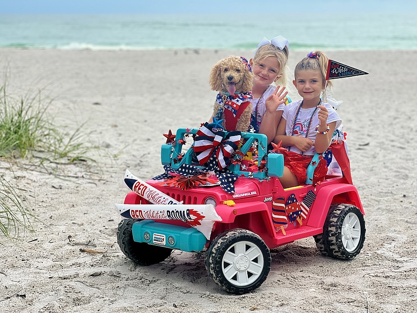 Lottie, the four-year-old miniature poodle, rides to victory in a toy car with Magnolia and Goldie Lowry in the 