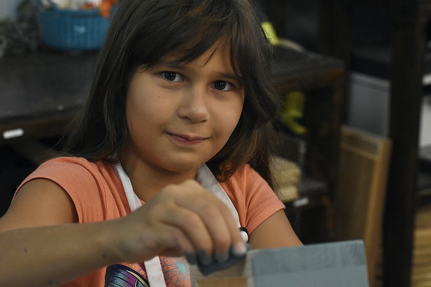 Taisa Tarima, 9, paints her plant holder.