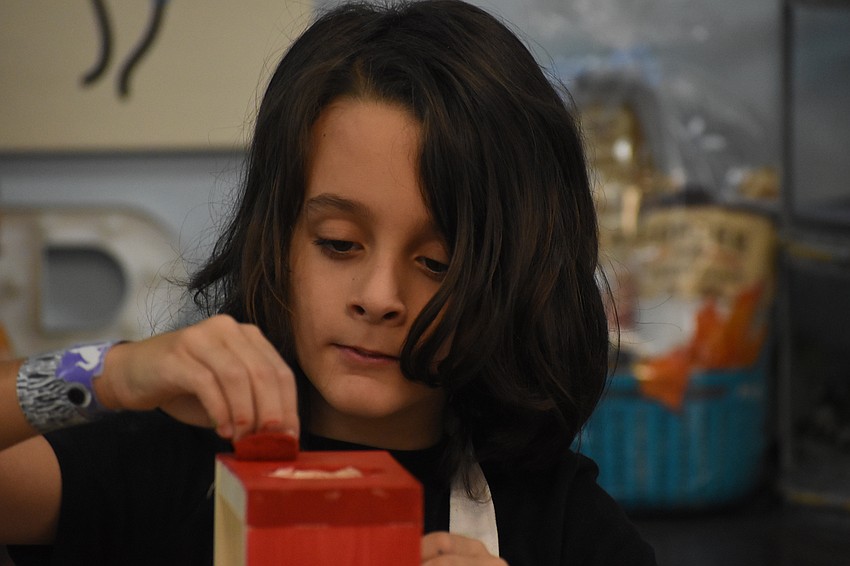 Mason Blumenthal, 9, dabs paint on his plant holder.