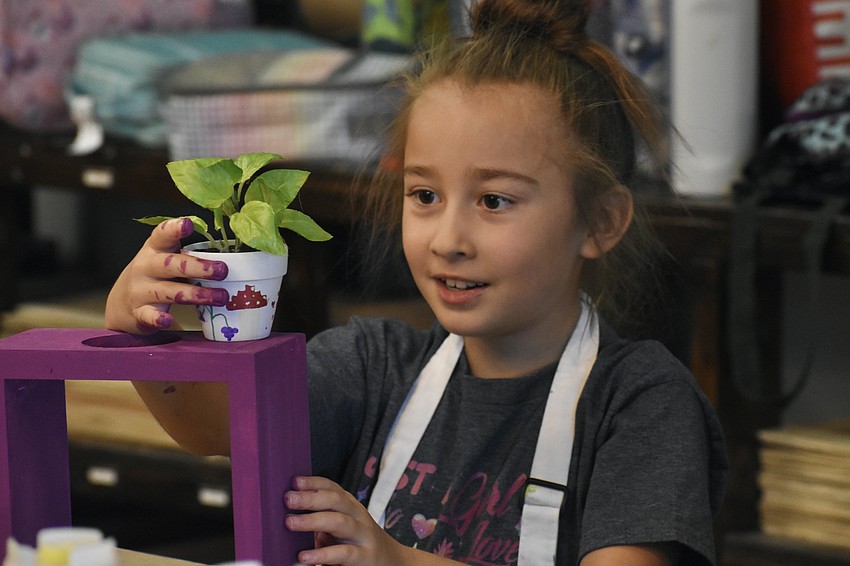 Olivia Sarkisova, 8, finishes her project by placing a plant on top.