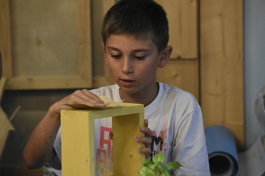 Chase Campbell, 8, performs sanding on his holder.